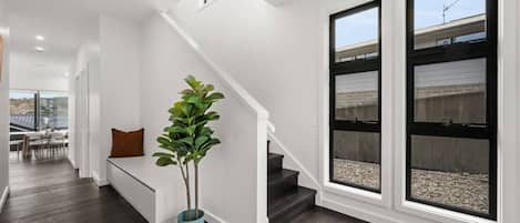 A modern interior with a staircase, a seating area, and large windows.