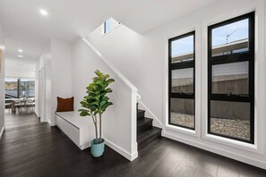 Een modern interieur met een trap, een zithoek en grote ramen.