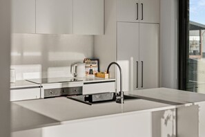 Eine moderne Küche mit weißen Schränken, einer Edelstahl-Spüle und einer Kaffeemaschine.