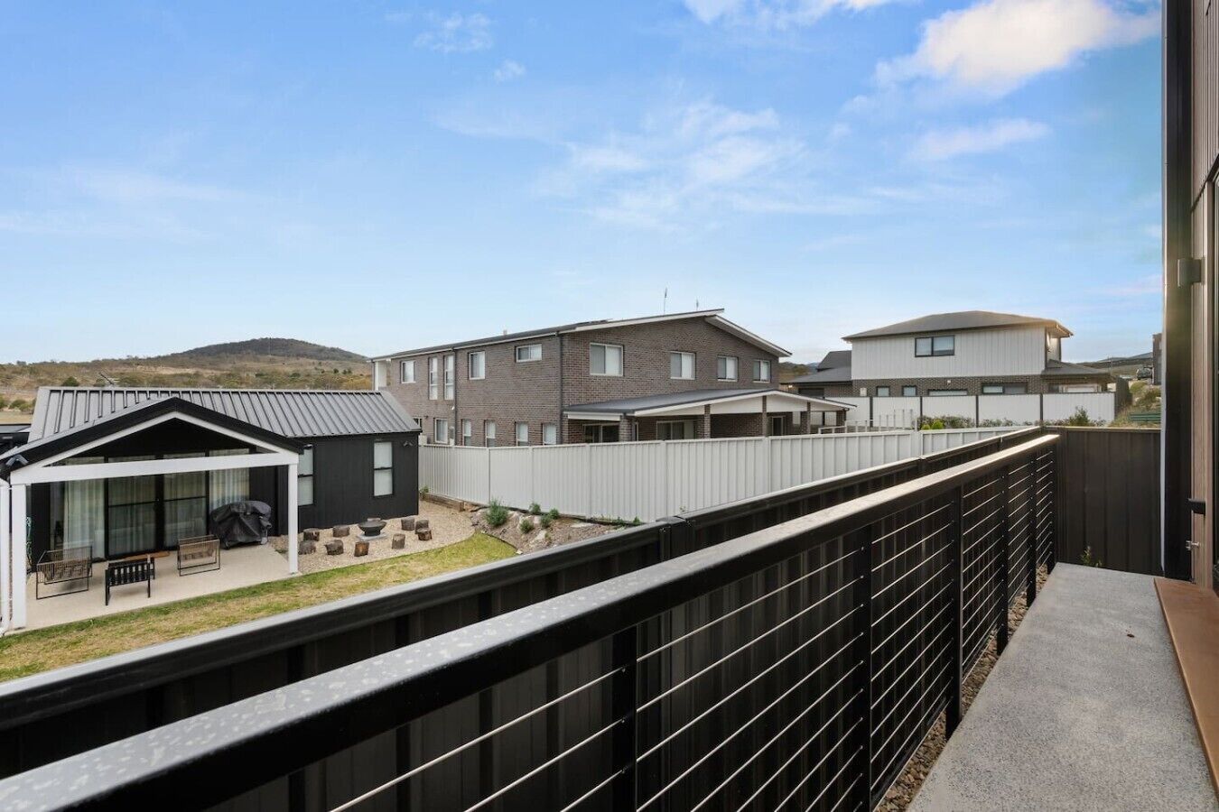 Un quartier résidentiel avec des maisons modernes, un espace extérieur aménagé et couvert, et une vue sur le paysage environnant.