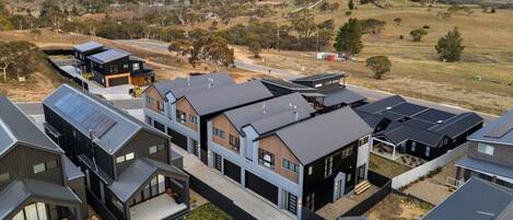 Zona residencial con casas modernas de techos planos, paneles solares y césped cuidado.
