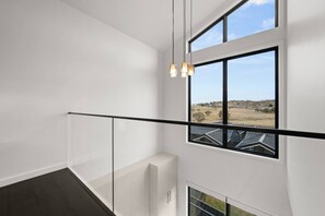 Een modern interieur met een glazen balustrade, grote ramen en uitzicht op de omgeving.