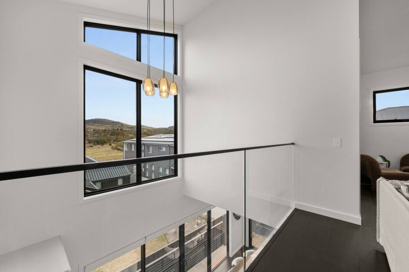 Et moderne interiør med en balkon, store vinduer og en hængende lampe.