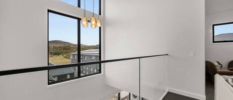 Et moderne interiør med en balkon, store vinduer og en hængende lampe.