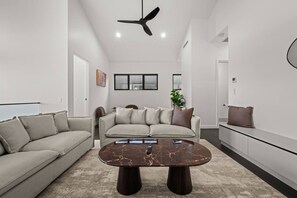 Ein modernes Wohnzimmer mit einer Couch, einem Couchtisch und einem Deckenventilator.