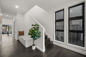 A modern interior with a staircase, a bench, and a potted plant. - Cozy Alpine Retreat | Fireplace & Mountain Charm (Jindabyne)