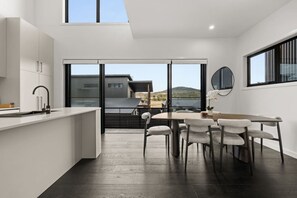 Eine moderne Küche mit Essbereich, großen Fenstern und Blick auf ein Gebäude und die Landschaft.