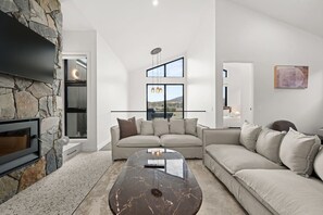 Uma sala de estar moderna com lareira de pedra, sofá modular e mesa de centro de mármore.