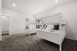 A room with bunk beds, a door, and a carpeted floor. - Cozy Alpine Retreat | Fireplace & Mountain Charm (Jindabyne)