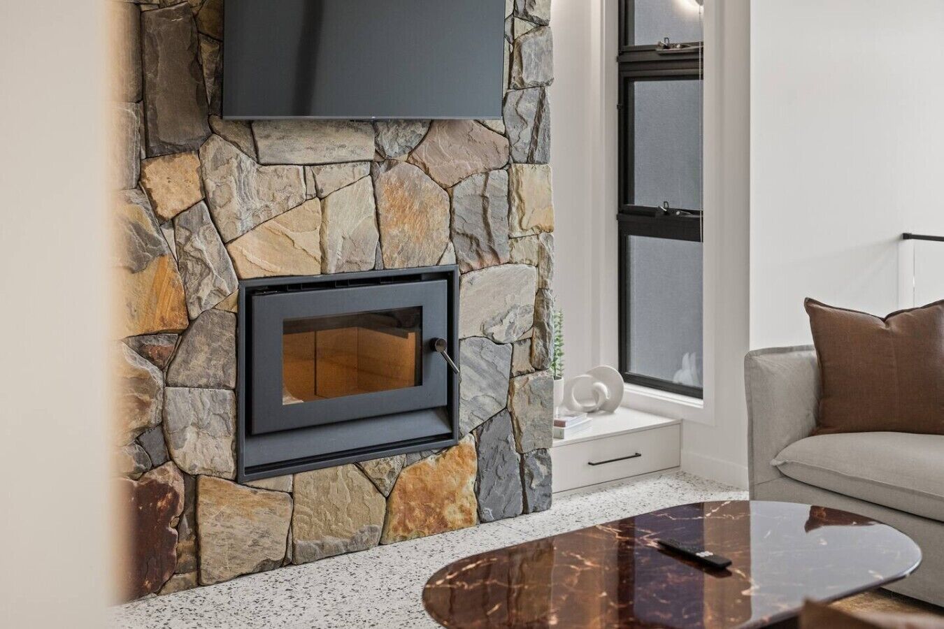 A stone wall with a built-in fireplace, a white sofa, and a coffee table.