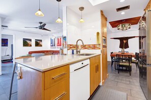 A modern kitchen with a central island, wooden cabinets, and a built-in dishwasher. - Stylish and fun second floor condo in exciting Palm Springs! (Palm Springs)