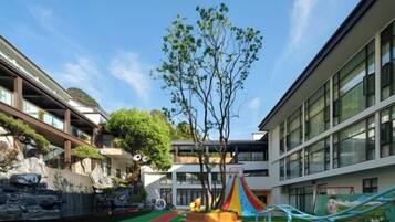 A courtyard with a playground, a tree, and a building with large windows.