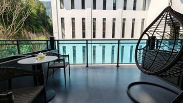 A balcony with a table and chairs, a hanging chair, and a view of a building with vertical windows.