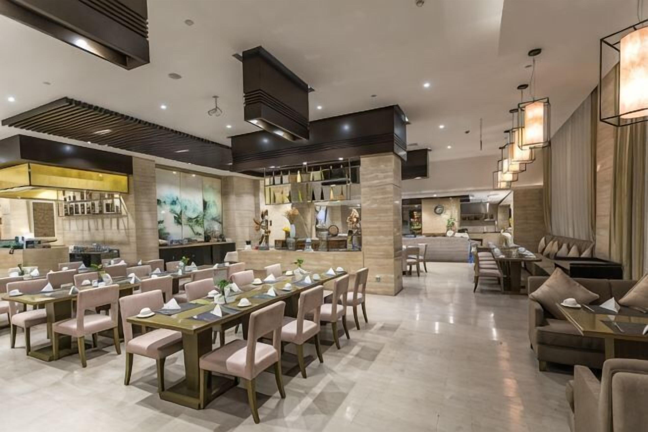 A spacious dining area with multiple tables and chairs, a bar area, and a kitchen in the background.