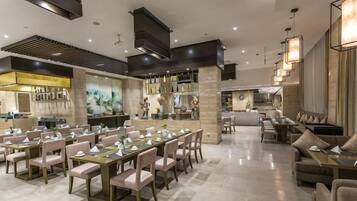 A spacious dining area with multiple tables and chairs, a bar area, and a kitchen in the background.