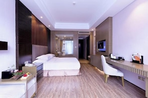 A hotel room with a large bed, a desk, and a television.