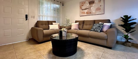 A living room with two sofas, a coffee table, and a potted plant.