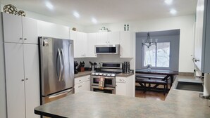 A modern kitchen with stainless steel appliances, a central island, and a dining area with a bench.