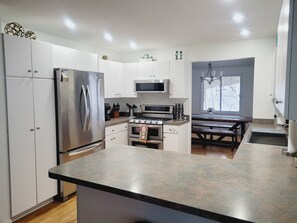 A modern kitchen with stainless steel appliances, a central island, and a dining area with a bench.
