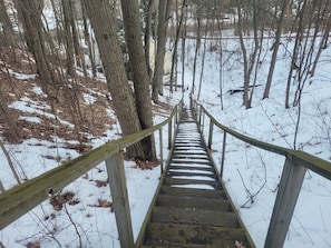 A wooden staircase leading into a snowy forest.