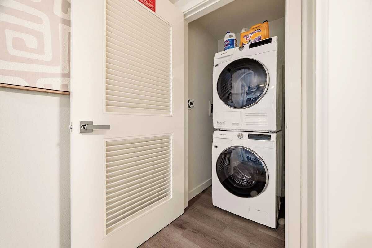 A laundry room with two stacked front-loading washing machines and a door with a vent.