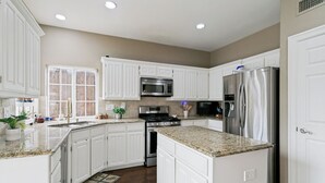 A kitchen with white cabinets, stainless steel appliances, and a granite countertop. - Private Pool Oasis- Spacious & Fully Furnished Dallas Home (Plano)