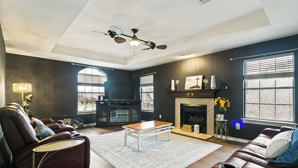 A modern living room with a fireplace, leather sofas, a coffee table, and a ceiling fan. - Private Pool Oasis- Spacious & Fully Furnished Dallas Home (Plano)