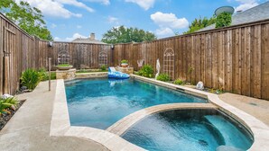 A backyard with a swimming pool, wooden fence, and a hot tub. - Private Pool Oasis- Spacious & Fully Furnished Dallas Home (Plano)