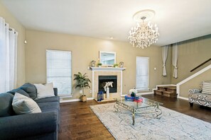 Un salon avec une cheminée, un lustre, un canapé et une table basse.