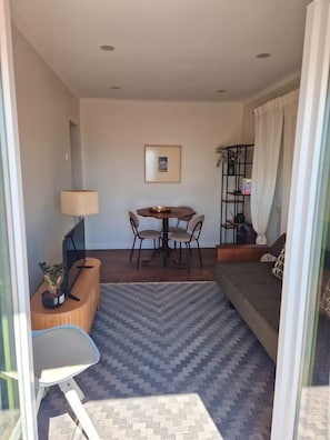 Ein modernes Wohnzimmer mit Esstisch, Stühlen, einer Couch, einem Fernseher und einem Bücherregal.