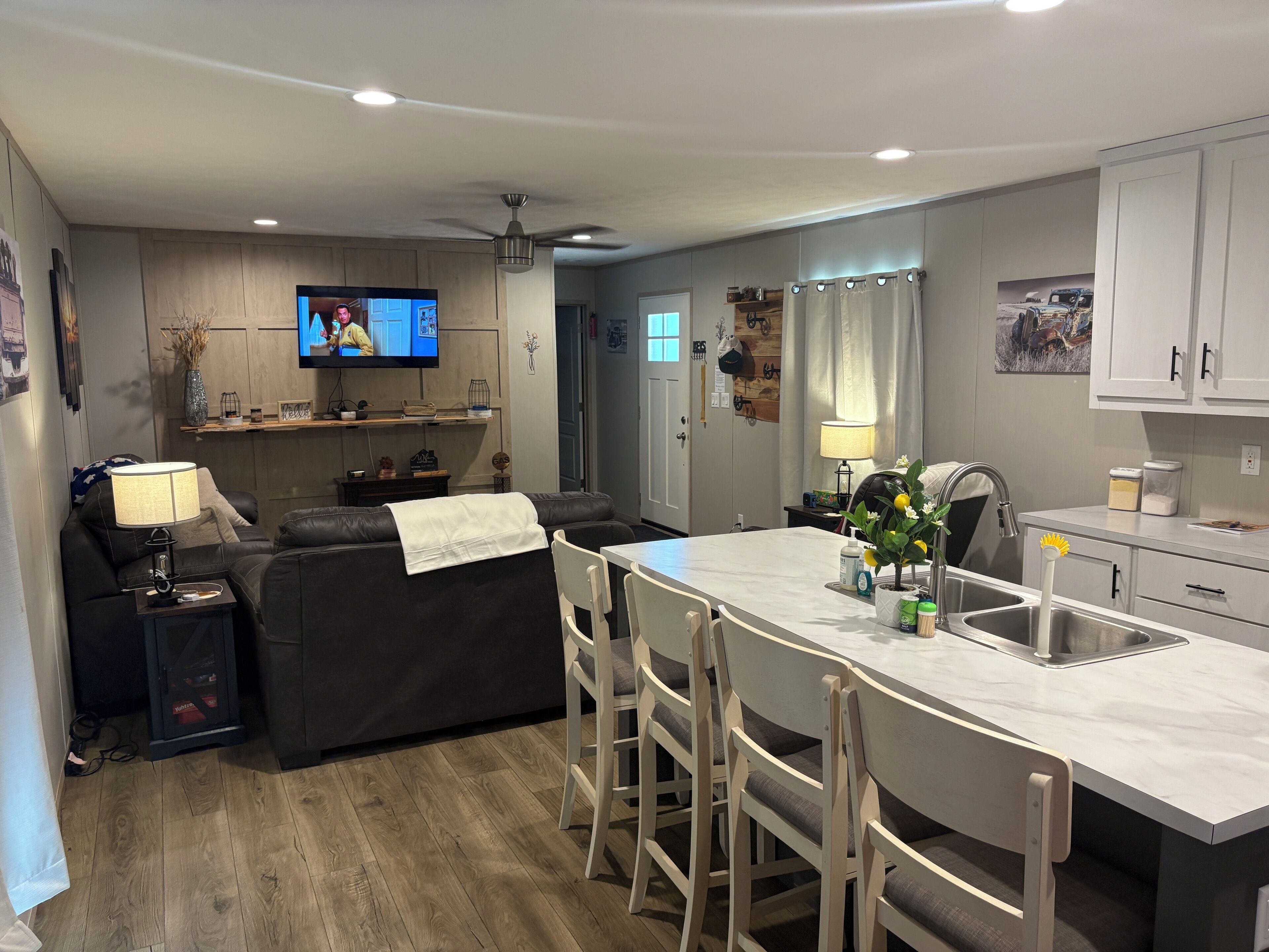A modern kitchen with a dining area, a TV, and a ceiling fan.