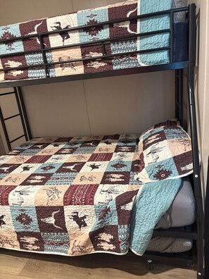 Un lit superposé avec une couvre-lit matelassée ornée de différents motifs et dessins.