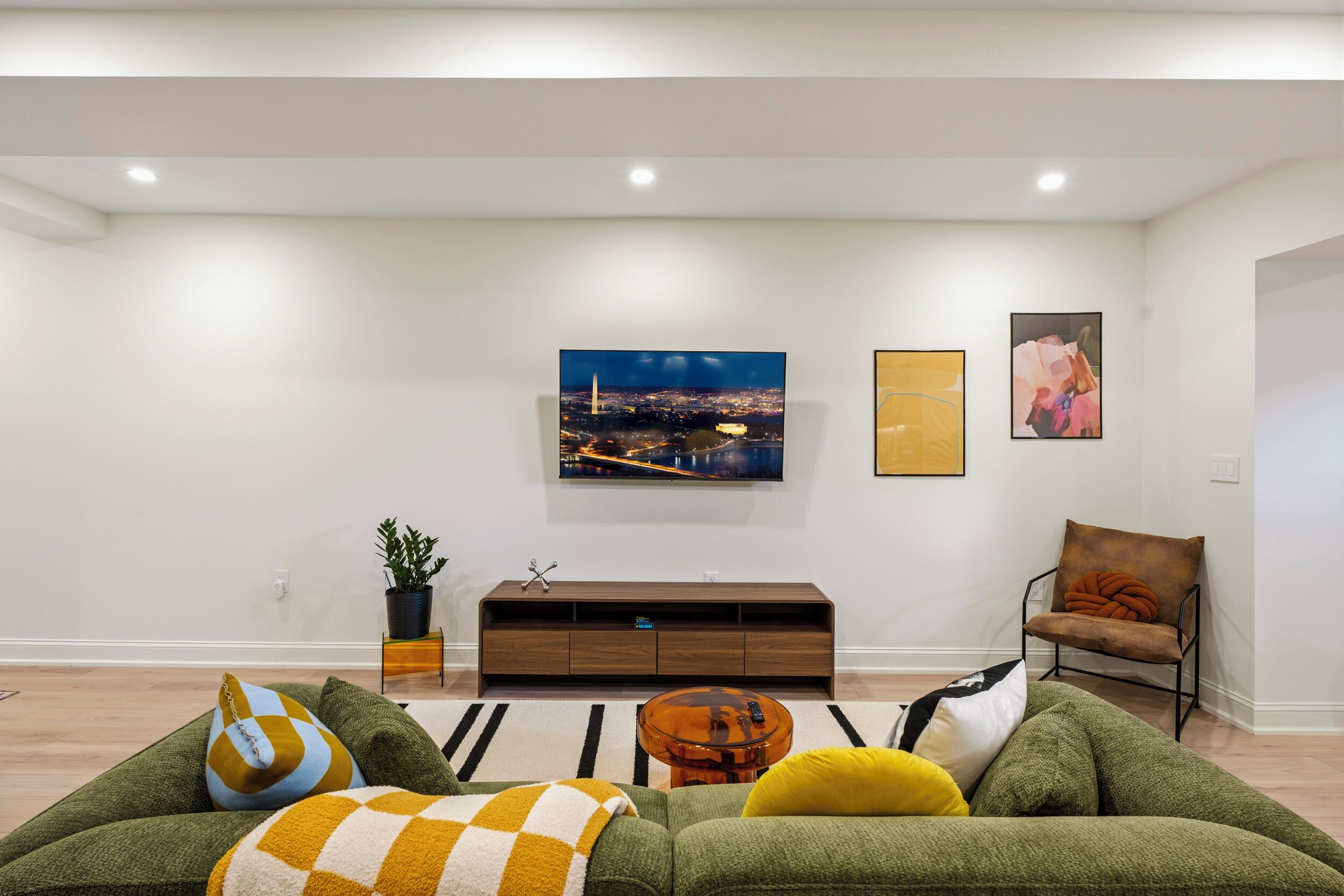 Ein modernes Wohnzimmer mit einer Couch, einem Couchtisch, einem an der Wand montierten Fernseher und einem Sessel.