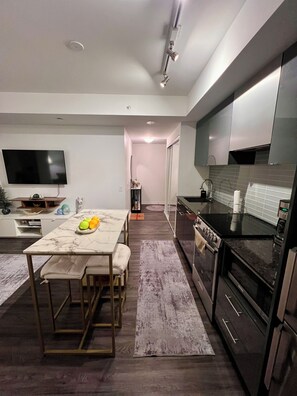 A modern kitchen with a black stove, stainless steel appliances, and a white tiled backsplash. - 1 Bedroom condo in the heart of Downtown Toronto (Toronto)