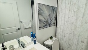A bathroom with a white sink, a toilet, a shower curtain, and a mirror.