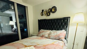 A hotel room with a bed, a nightstand, a lamp, and decorative wall art.