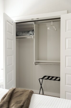 A white closet with open doors, a hanging rod, and a drying rack. - E101: 3BR near UCO | 2 King+ Private Bath Every BR (Edmond)