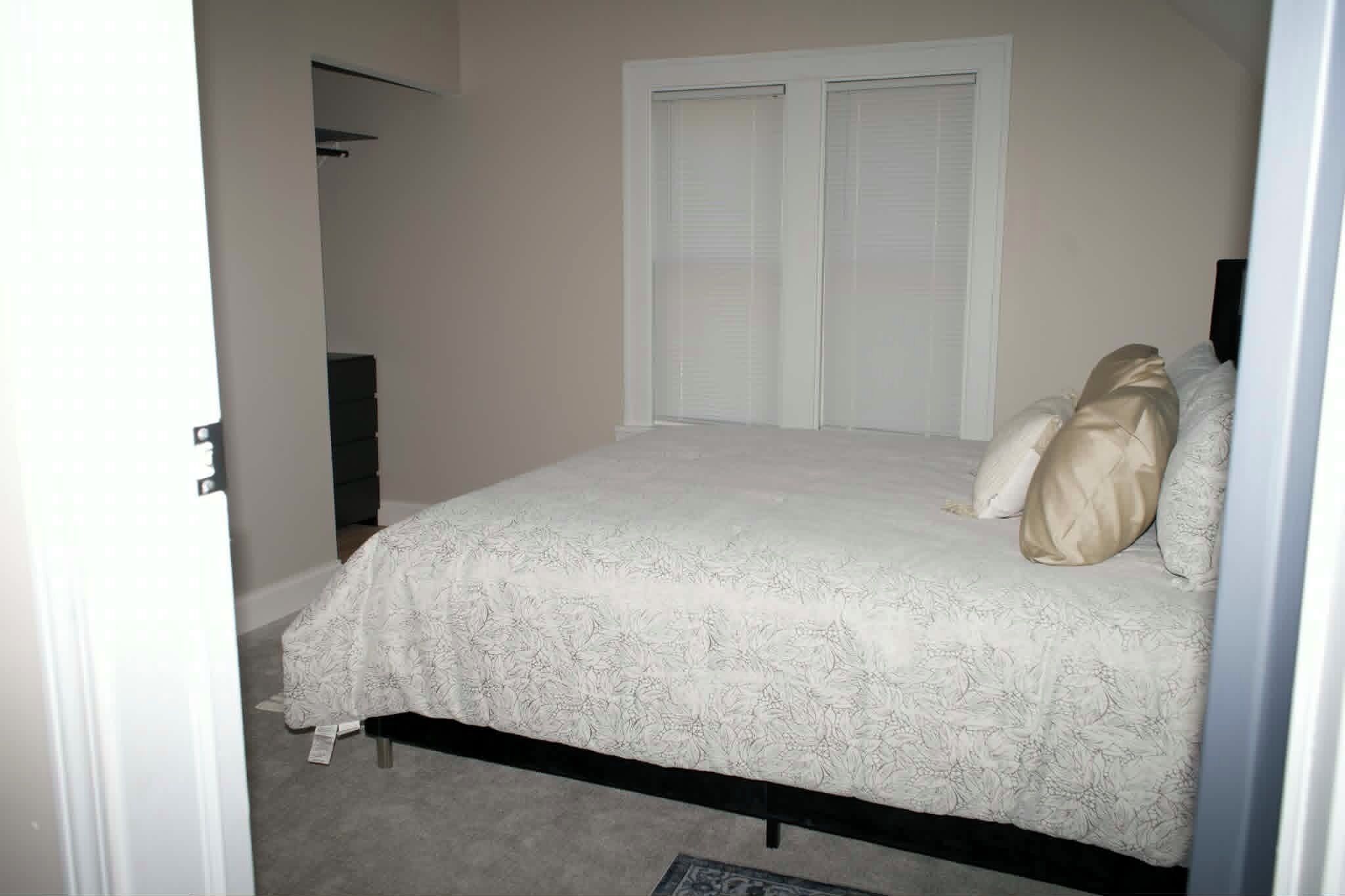 Un dormitorio con cama, dos puertas y cómoda.