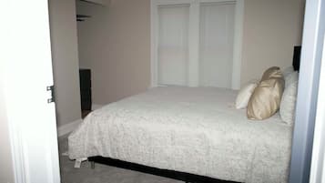 Un dormitorio con cama, dos puertas y cómoda.