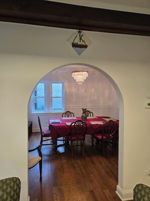 A dining area with a red tablecloth, wooden chairs, and a chandelier. - American Tudor Revival, 8-beds, 4 bedrooms, 3 sofa beds, 3 full bath, all new. (Downers Grove)