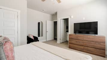 A bedroom with a bed, a dresser, a television, and a ceiling fan.