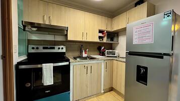 A compact kitchen with a stove, oven, microwave, and refrigerator.