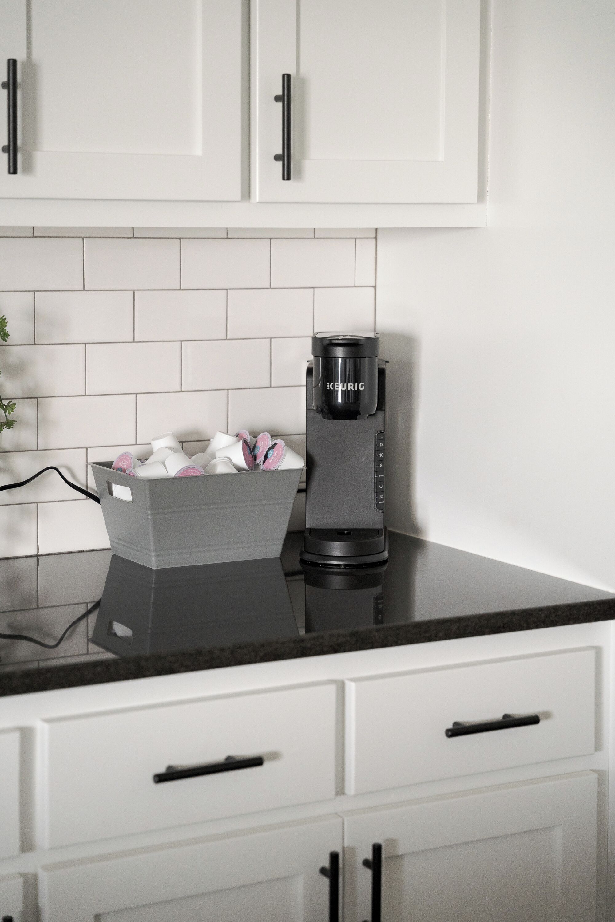 Eine moderne Küche mit weißen Schränken, einer schwarzen Arbeitsplatte und einer Kaffeemaschine.