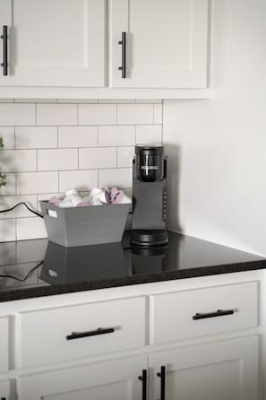 A modern kitchen with white cabinets, a black countertop, and a coffee maker. - E102: 3BR near UCO | 2 King+ Private Bath Every BR (Edmond)