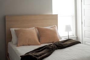 A neatly made bed with a brown blanket, two pillows, and a wooden headboard. - E102: 3BR near UCO | 2 King+ Private Bath Every BR (Edmond)
