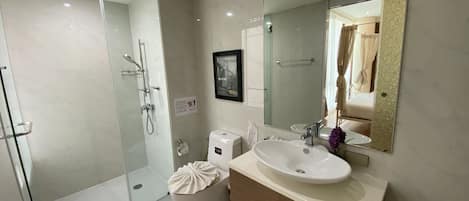 A modern bathroom with a glass-enclosed shower, a white sink, and a large mirror.