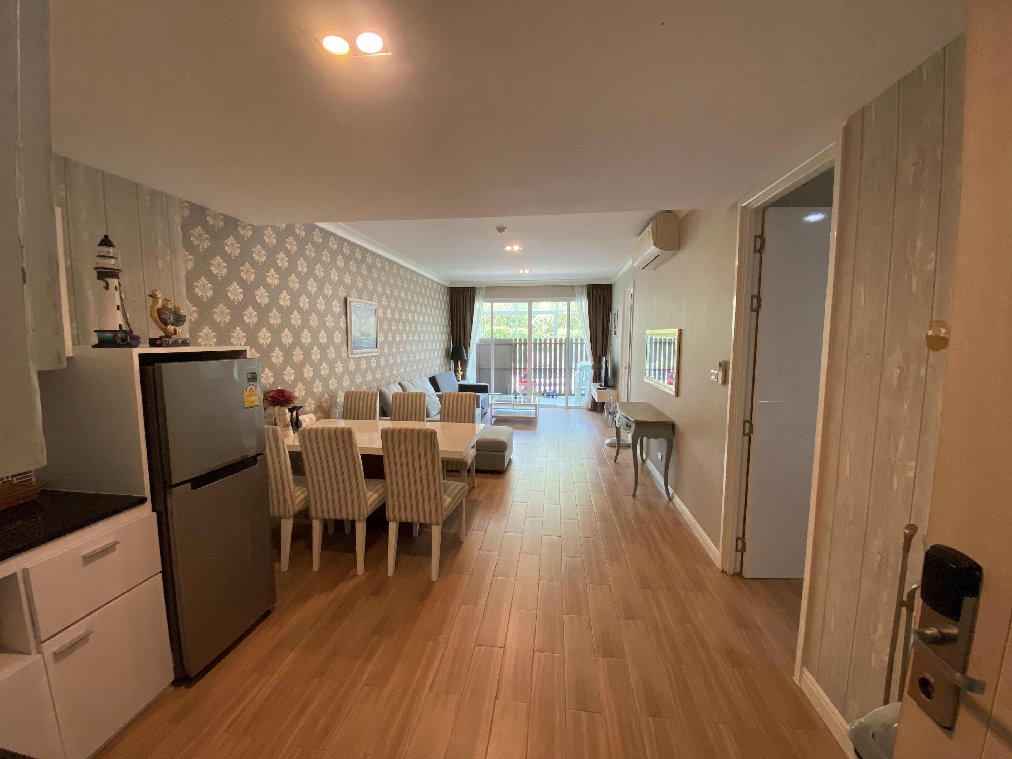 A modern kitchen with a dining area, wooden flooring, and a view to the outside.
