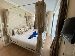 Habitación de hotel con cama con dosel, televisor de pantalla plana y minibar.
