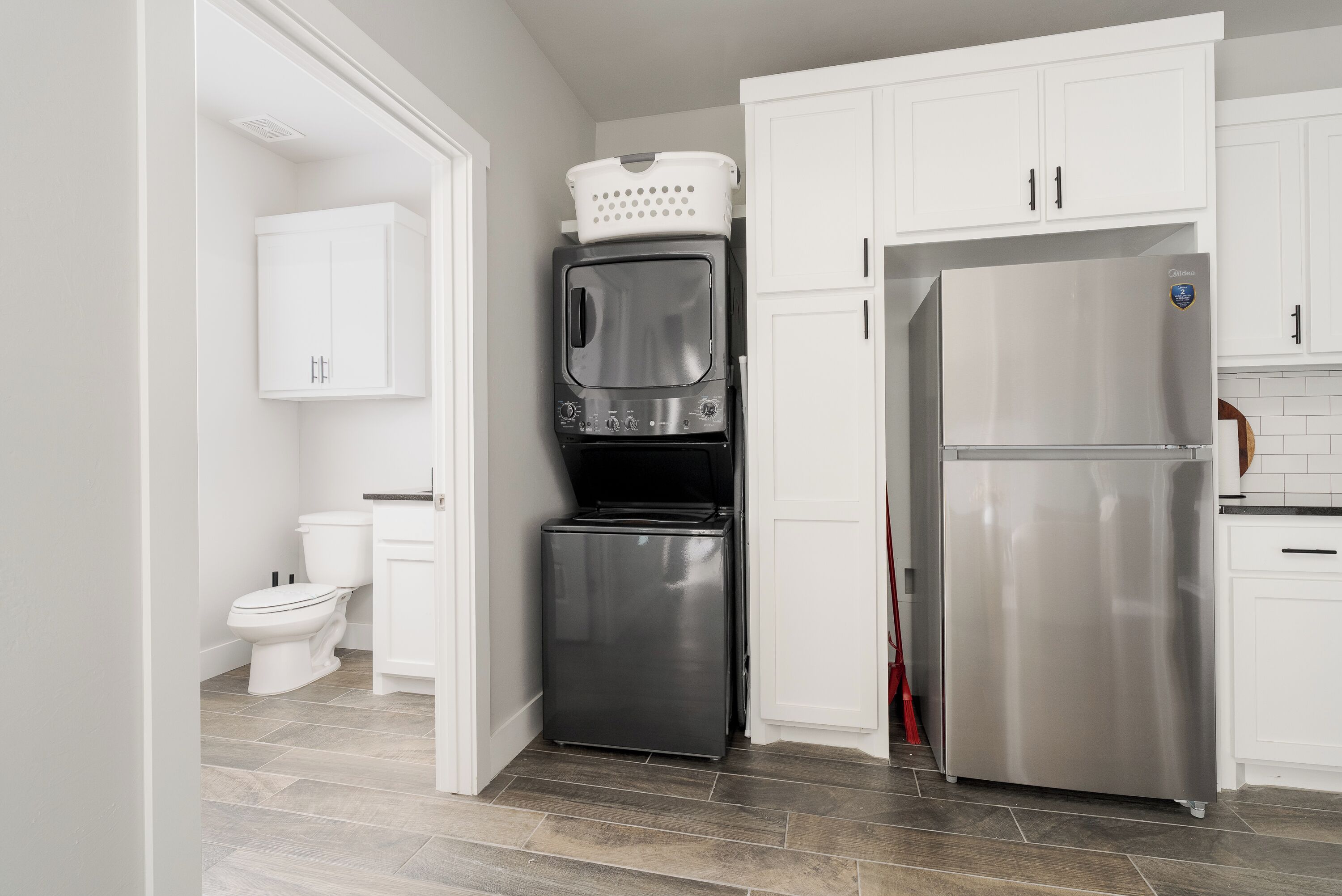 A compact kitchen with a stainless steel refrigerator, a built-in oven, and a washing machine.