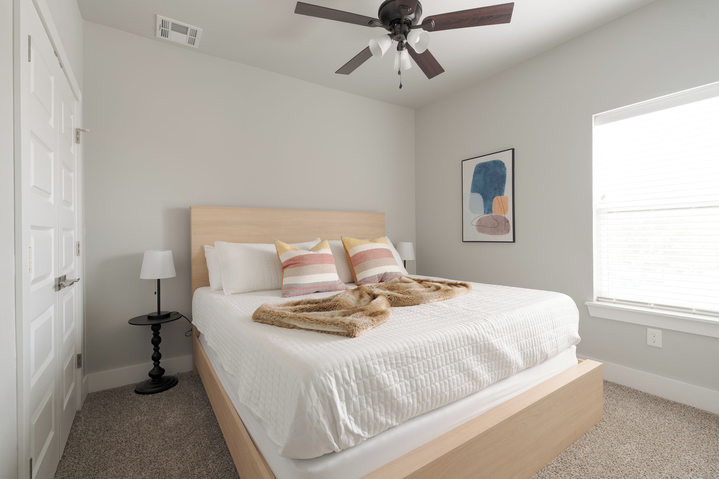 Ein Schlafzimmer mit Bett, Deckenventilator, Fenster und Tür.